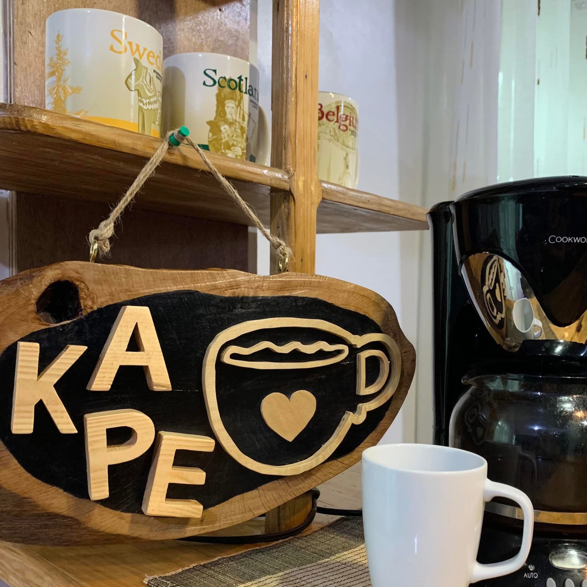 Live-edge wood slice sign with KAPE letters and a wooden coffee cup with a heart