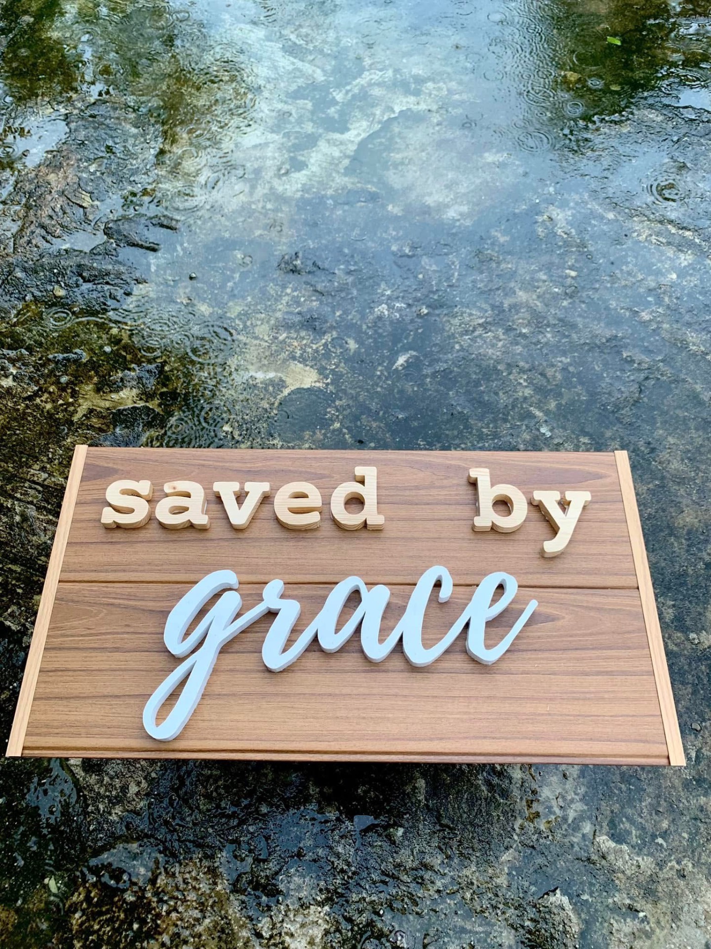 Warm brown slat wood sign with 'saved by' in natural pine and 'grace' in white script